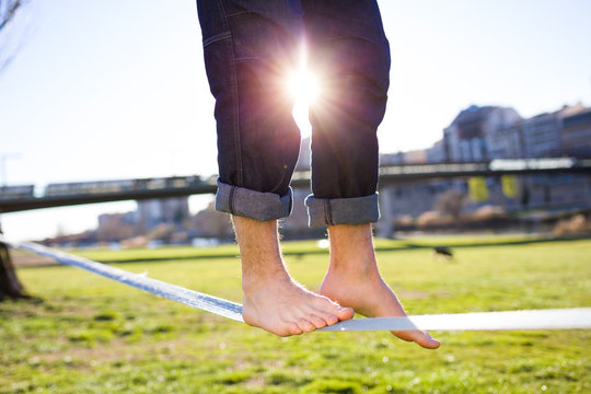 Legs Of A Man Walking On Slackline In The Park.