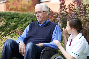 Fototapeta na wymiar Nurse Comforting Senior Man In Wheelchair