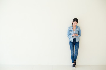Woman using cellphone and standing against big wall