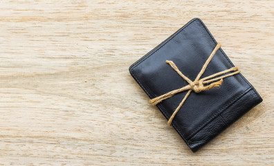 black leather wallet with ropes on wood background.The concept o