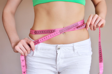 Close up of female hands measuring waist with measuring tape