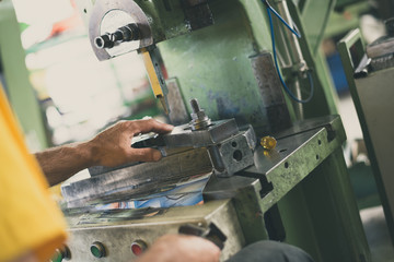 Close up photo of dirty workers hand doing some job on big metalworking machine. Selective focus.