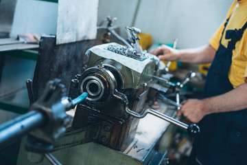 Close up photo of dirty workers hand doing some job on big metalworking machine. Selective focus.