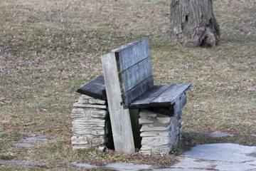 Two-seated rough looking park bench in a small park. 

