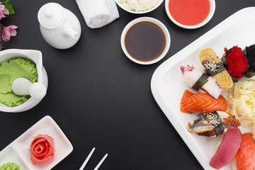 Fototapeta na wymiar Sushi nigiri on a white plate with ginger wasabi and sauces over black background