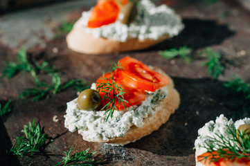 Vegetarian starter appetizer. Bruschetta with crème cheese olives tomatoes and greens