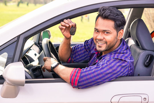 Young indian happy man inside new car - Cheerful asian man showing car key outdoor - Successful businessman inside automobile looking at camera and smiling - Concept of happiness and success