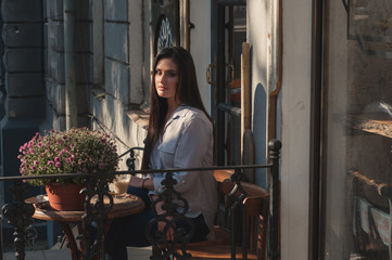 Portrait of beautiful sexy happy brunette model girl sitting in the cafe coffee shop with cup of cappuccino alone during sunny warm day 