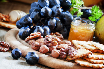 Wooden dish with appetizers to red wine, selective focus