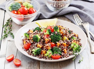 Quinoa salad with broccoli,sweet potatoes and tomatoes on a rustic wooden table.Superfoods concept.Selective focus