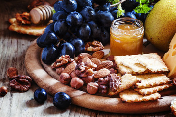 Wooden dish with appetizers to red wine, selective focus