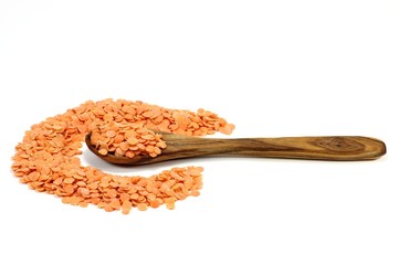 Löffel aus Olivenholz mit ungekochten roten Linsen isoliert auf weißem Hintergrund