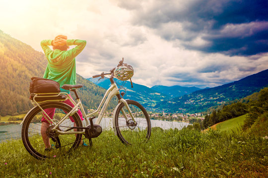 sportive woman with e-bike resting above a lake