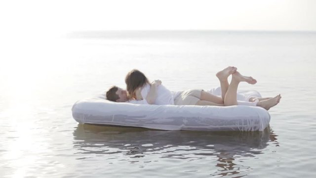 Сouple lying on airbed mattress on the water