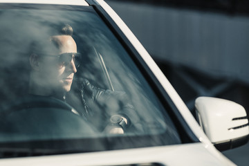 Fototapeta na wymiar Fashionable Handsome Man in Sunglasses Sitting in his Luxury on Driver Seat. Luxury Life. Lifestyle photo. Ideal for commercial