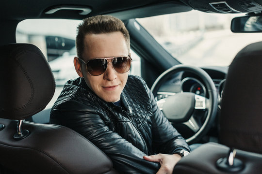 Fashionable Handsome Man in Sunglasses Sitting in his Luxury on Driver Seat. Luxury Life. Lifestyle photo. Ideal for commercial. Rental car concept
