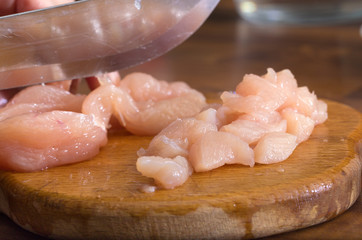 The crude chicken meat cut on pieces on a wooden board