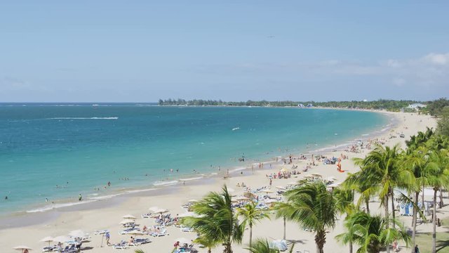 Isla Verde Beach in Puerto Rico. Tourist destination with beach resort and cruise ship tourists, Unrecognizable people enjoying beach summer holiday vacation on caribbean travel. SLOW MOTION RED EPIC.