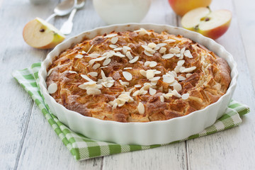 Homemade apple pie with in a white baking form on a white wooden background, closeup, selective focus