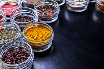 Spices on black background in special jars. Food