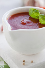 Fresh homemade tomato sauce in a white bowl on a white board, closeup, selective focus
