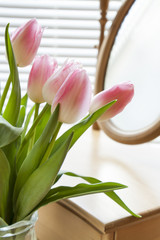 Beautiful bouquet of pink tulips and mirror on backlight background