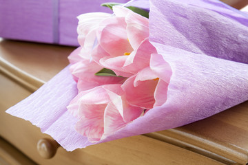 Pink tulips in violet paper, gift and mirror, backlight background