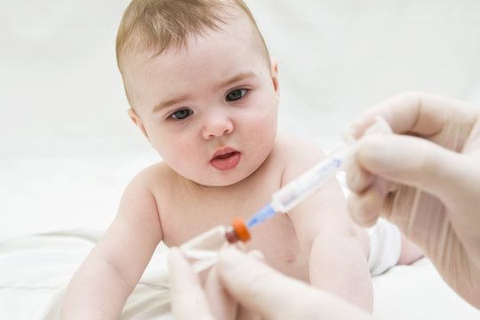 Baby girl  is starring on syringe with  vaccine