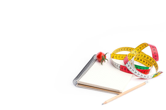 Notebook with metering tape, pencil and tomatoes on white