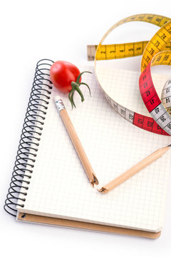 Notebook with metering tape, pencil and tomatoes on white