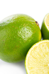 Whole and sliced fresh limes on on white, DOF