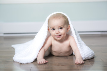 Baby in diaper covered with towel, in his house