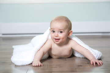 Baby in diaper covered with towel, in his house