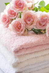 Obraz na płótnie Canvas Folded towels on bathroom counter with ligh pink roses
