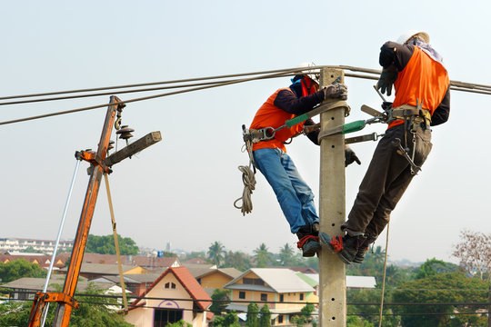 Electrician lineman repairman worker at climbing work on electric post power pole, Thai language same safty fist in English language