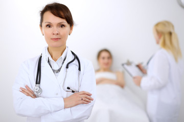Female doctor smiling on the background with patient and his doctor
