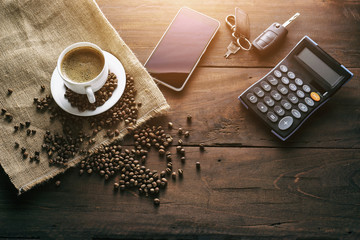 A cup of coffee on the table and calculator and smartphone, vintage dark stly