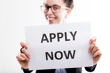 apply now sign hold by a young smiling woman