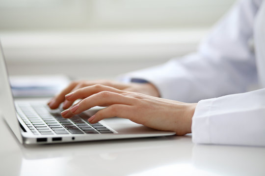 Female doctor typing on laptop, close up