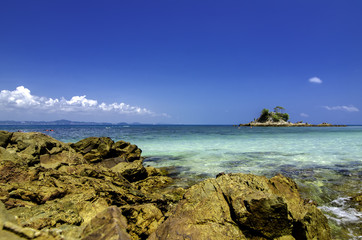 Stunning image of tropical beach at Kapas Island, Malaysia. Wet Rock and crystal clear sea water with blue sky background