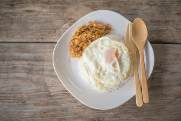 chicken fried garlic and egg fried with cooked rice on wood table