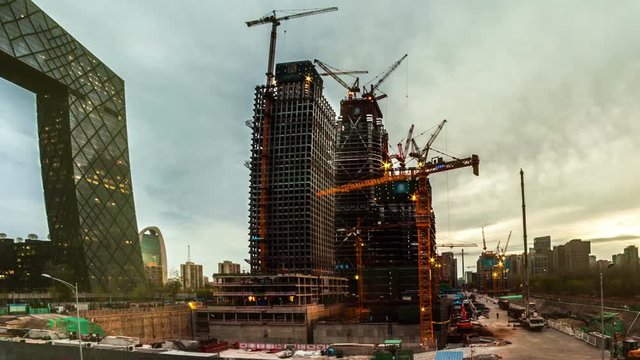 Construction of concrete buildings on background moving clouds
