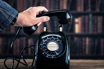 黒電話のダイヤルを回る男性の手