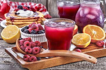 juice of raspberries and blackberries with citrus and pancakes on the table