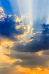 Clouds and a blue sky with a sunbeam shining through, evening time.