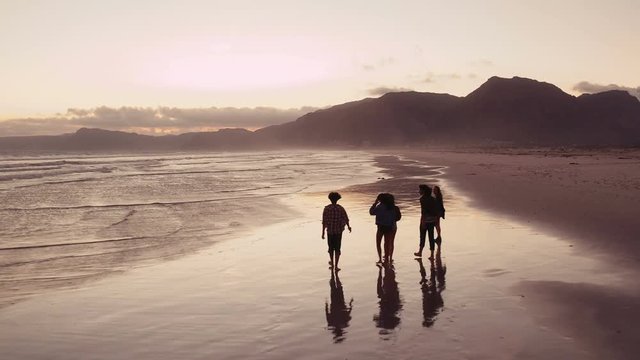 Teen friends enjoying a walk at beach on sunset