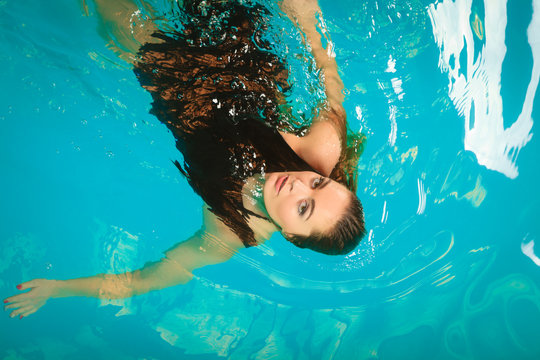 Woman floating relaxing in swimming pool water.