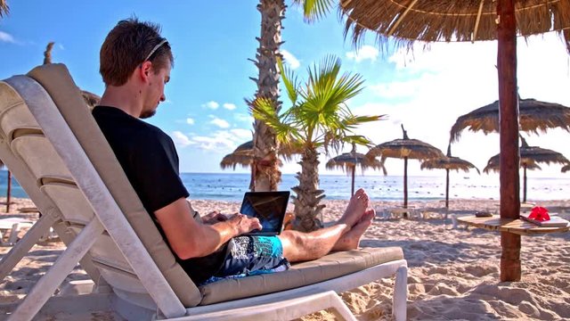 Person at the sand beach typing on laptop