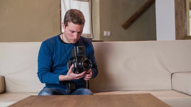 Man with retro photo camera on sofa