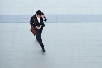 Businessman calling on the phone when walking outdoors